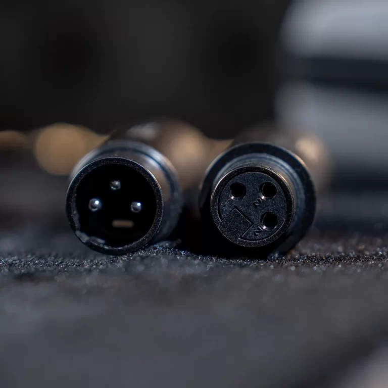 Close-up of two round multi-pin electrical connectors with pin holes on a dark surface. ขายราคาพิเศษ