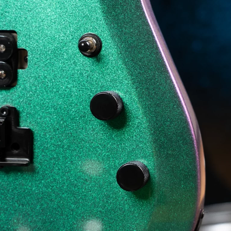 Close-up of a green metallic electric guitar body with three black knurled control knobs and part of a pickup/bridge on the left edge. ขายราคาพิเศษ