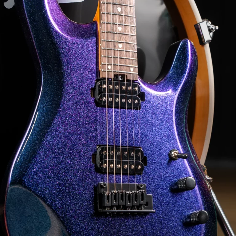 Close-up of a glittery purple electric guitar body with two black humbucker pickups, maple neck, and control knobs. ขายราคาพิเศษ