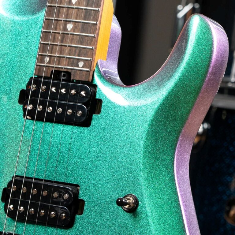 Close-up of a glittery teal-green electric guitar body with purple edge, showing dual humbucker pickups and strings near the neck. ขายราคาพิเศษ