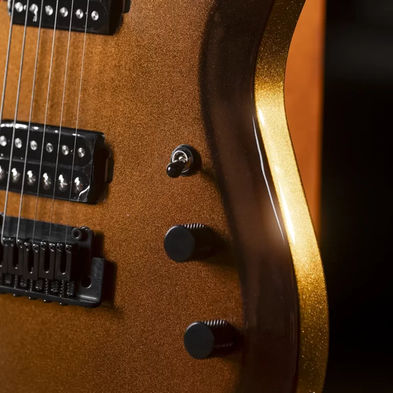 Close-up of an orange glittery electric guitar body showing two humbucker pickups, a toggle switch, and control knobs. ขายราคาพิเศษ