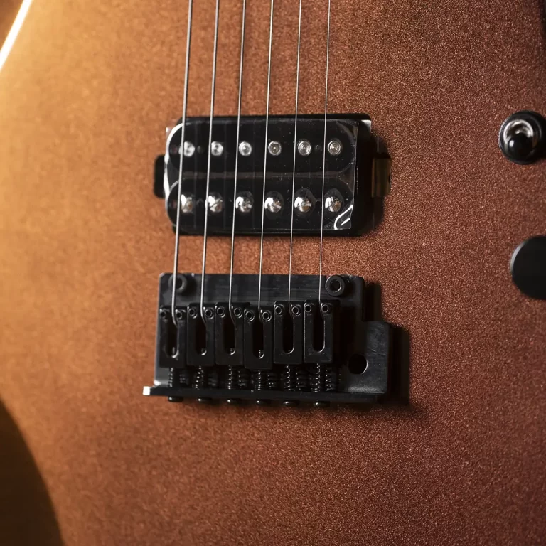 Close-up of a brown metallic electric guitar showing a black fixed bridge and dual pickups with six guitar strings above them ขายราคาพิเศษ