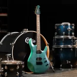 Green electric guitar leaning against a teal-speckled drum set in a music studio. ขายราคาพิเศษ