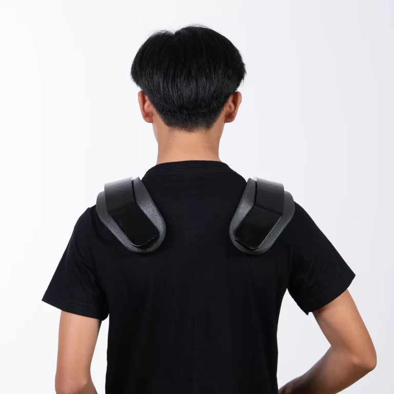 Person wearing a pair of shoulder massage devices attached over the shoulders, seen from behind. ขายราคาพิเศษ