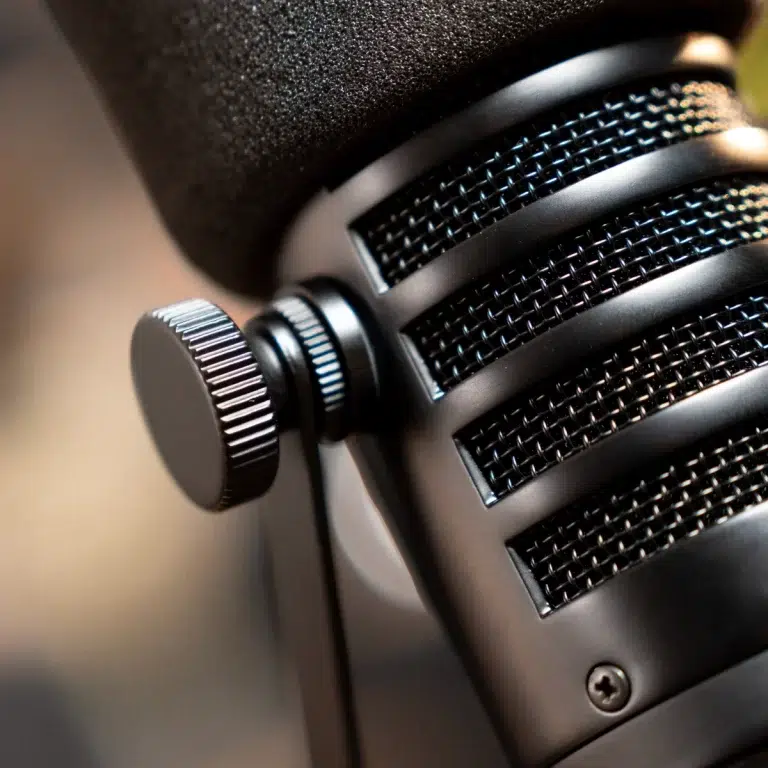 Close-up of a studio microphone showing its black mesh grille and knurled control knob. ขายราคาพิเศษ