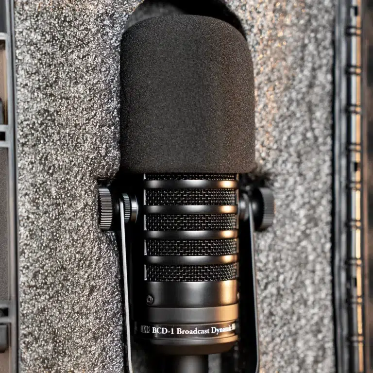 Close-up of a black dynamic broadcast microphone with a foam windscreen mounted in a foam-lined case, the label BCD-1 Broadcast Dynamic visible on the mic. ขายราคาพิเศษ