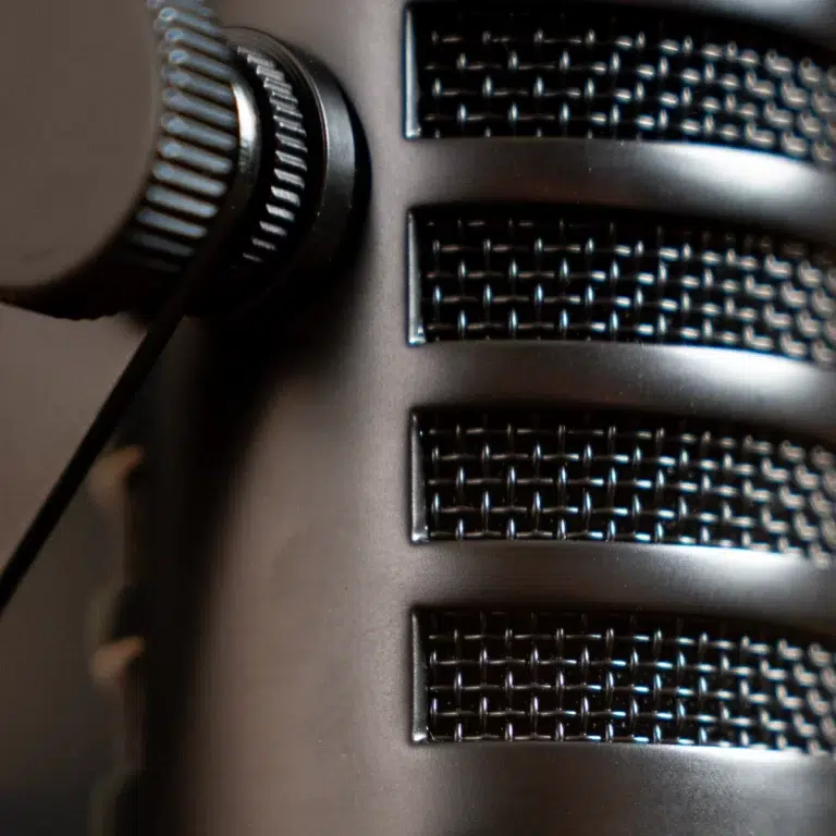 Close-up of a black desktop microphone with a knurled adjustment knob on the left and a textured grille on the right ขายราคาพิเศษ