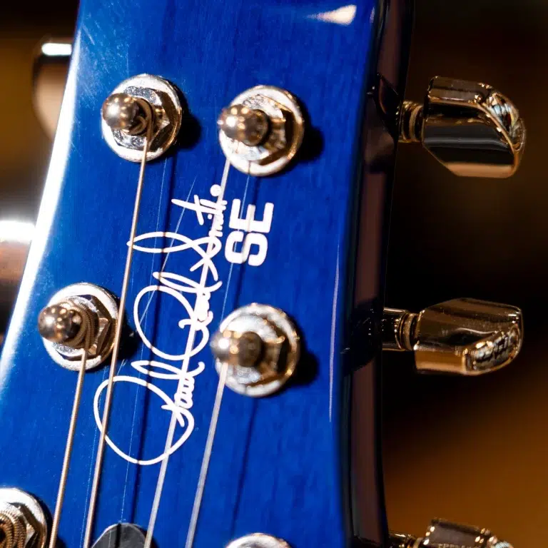 Close-up of a blue electric guitar headstock with six chrome tuners and strings, Gibson branding visible ขายราคาพิเศษ