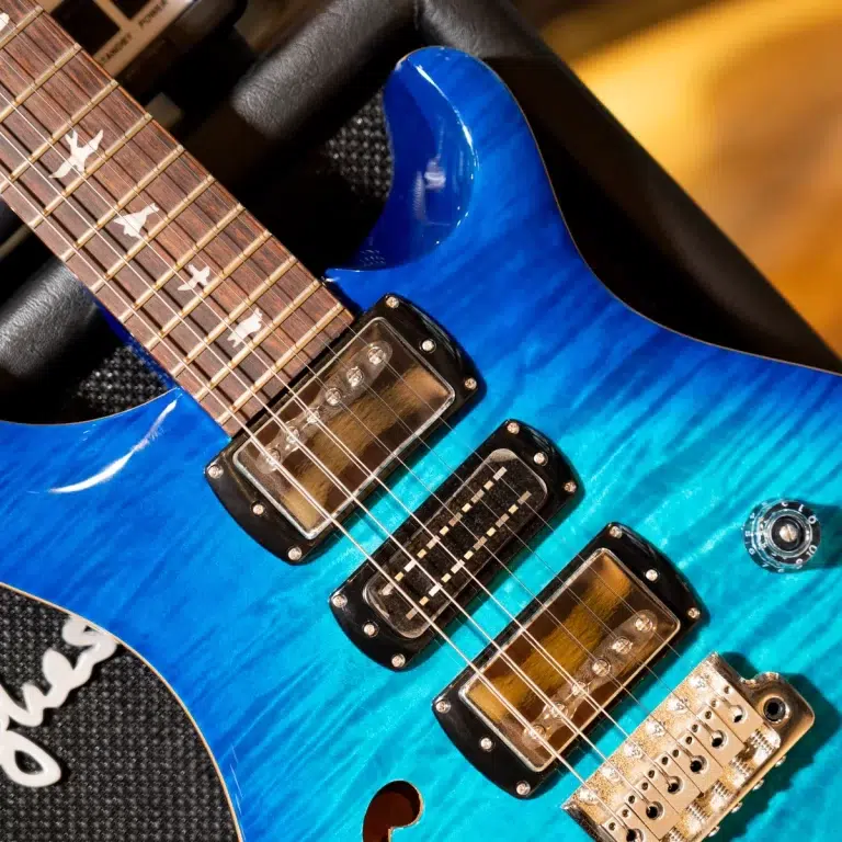 Close-up of a blue electric guitar showing two humbucker pickups, maple neck, and a metal bridge. ขายราคาพิเศษ