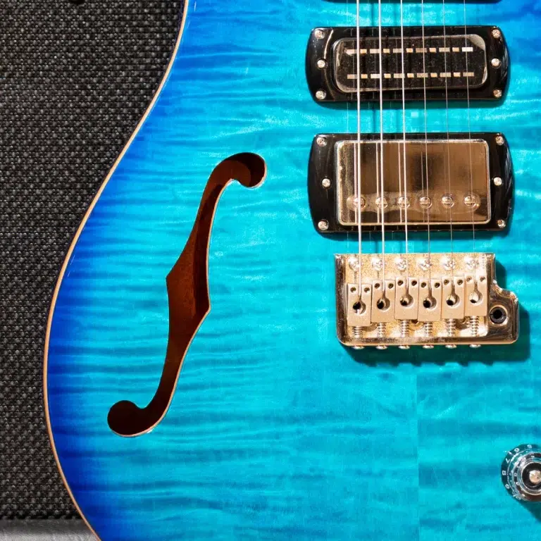 Close-up of a blue electric guitar body with an f-hole, pickups, and a chrome bridge. ขายราคาพิเศษ