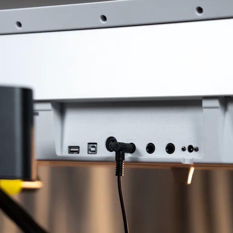 Rear panel of a gray electronic device with a plugged-in power cable and USB and audio ports visible behind it. ขายราคาพิเศษ