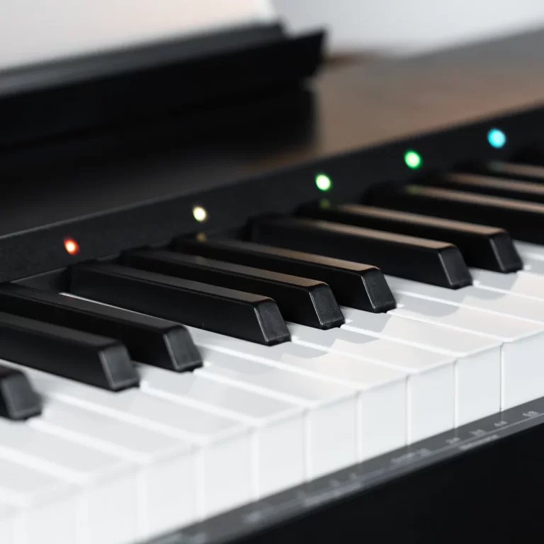 Close-up of a digital piano keyboard with glowing colored LEDs above the keys (green, red, blue) indicating status or presets. ขายราคาพิเศษ
