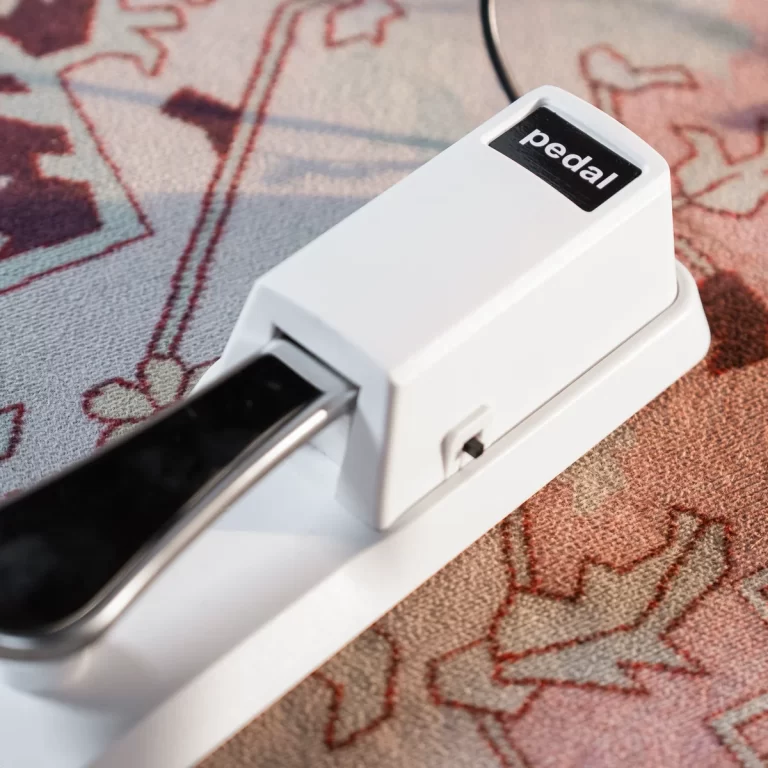 Close-up of a white foot pedal labeled 'pedal' resting on a power strip on a patterned rug. ขายราคาพิเศษ