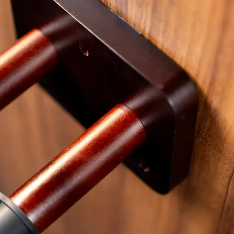 Close-up of a dark brown wooden door lever with a black metal mounting plate on a wooden door. ขายราคาพิเศษ