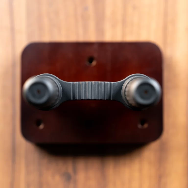Top-down view of a dark dual-knob handle attached to a wooden square plate. ขายราคาพิเศษ