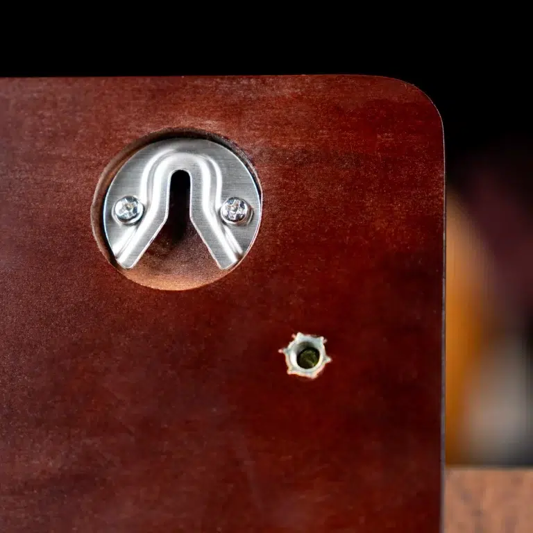 Close-up of a silver U-shaped latch embedded in dark wood with two screws visible in a circular metal plate. ขายราคาพิเศษ