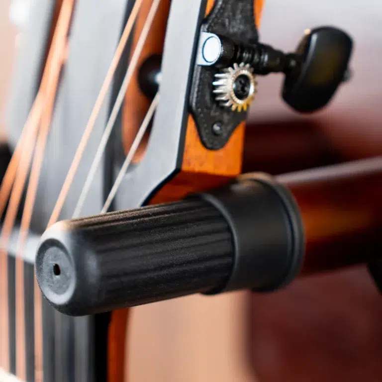 Close-up of a guitar headstock with a gear tuning peg and strings, mounted on a stand. ขายราคาพิเศษ