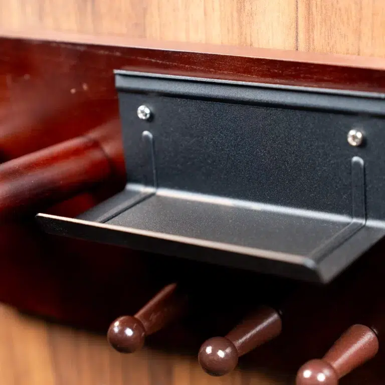 Close-up of a black metal pull-out tray mounted under a wooden surface, with three brown wooden pegs in the foreground. ขายราคาพิเศษ