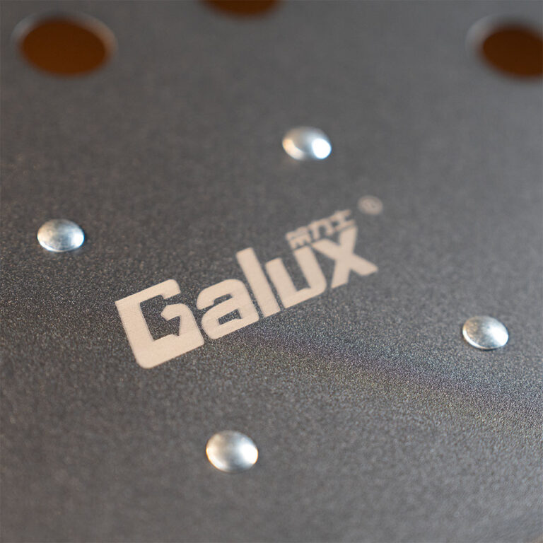 Close-up of a gray textured metal surface with round metal studs and a white 'Galux' logo. ขายราคาพิเศษ