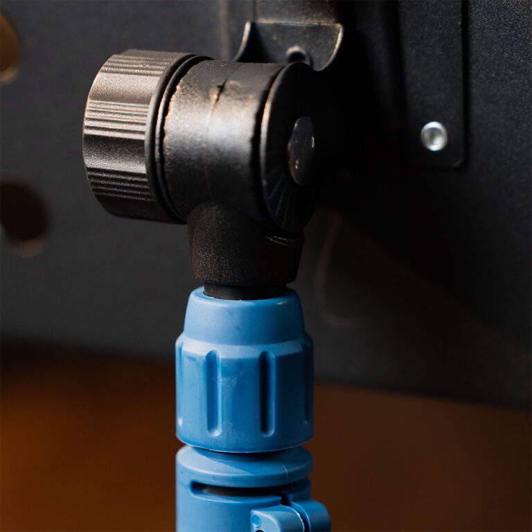 Close-up of a blue plastic tripod quick-release connector attached to a black swivel head on a dark surface ขายราคาพิเศษ