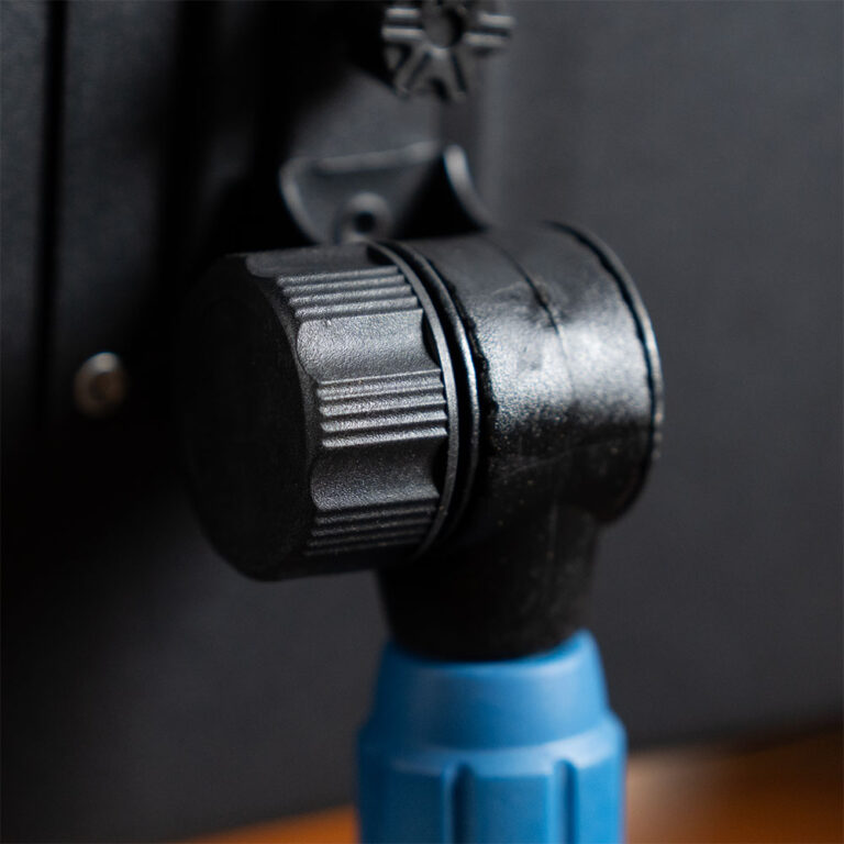 Close-up of a textured black tripod head knob with a blue quick-release lever below it. ขายราคาพิเศษ