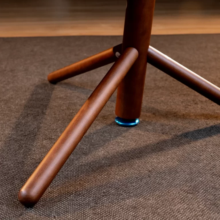 Wooden chair leg with a blue protective glide resting on a dark carpet. ขายราคาพิเศษ