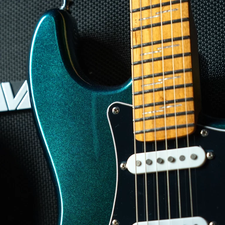 Close-up of a teal metallic electric guitar body with a maple neck and white bridge pickup, strings visible over frets. ขายราคาพิเศษ