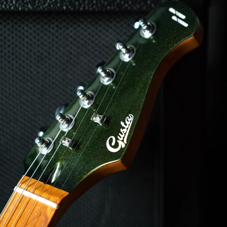 Close-up of a green glitter electric guitar headstock with tuning pegs and six strings. ขายราคาพิเศษ