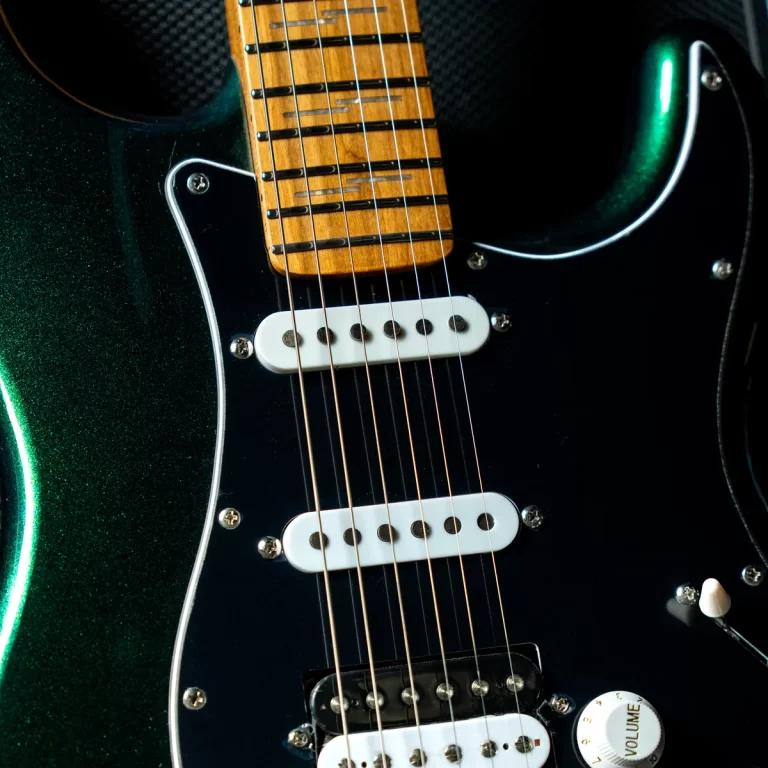 Close-up of a green metallic electric guitar body with a wooden neck, two white pickups, and multiple strings visible. ขายราคาพิเศษ