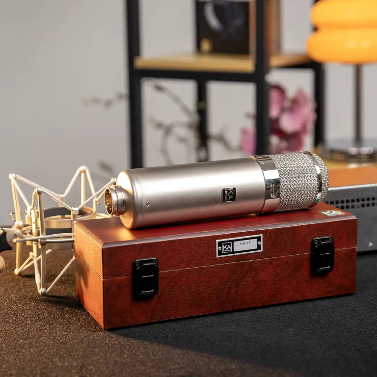 Silver studio microphone resting on a wooden carrying case in a recording setup. ขายราคาพิเศษ