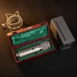 Condenser microphone in a wooden case with green lining, shock mount, and a separate power supply on a dark surface. ขายราคาพิเศษ
