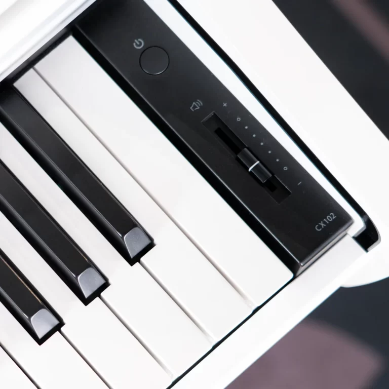 Close-up of a white digital piano keyboard with black keys and a right-side control panel labeled CX102, featuring a slider and power button ขายราคาพิเศษ