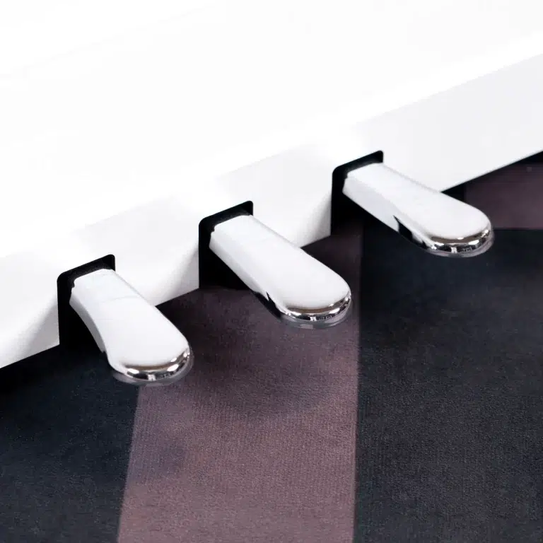 Close-up of white piano keys with shiny chrome ends, viewed from the side against a dark striped background ขายราคาพิเศษ