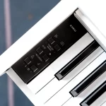 Close-up of a white Kawai piano with a black control panel showing buttons labeled Concert Magic and Recorder, next to glossy keys. ขายราคาพิเศษ