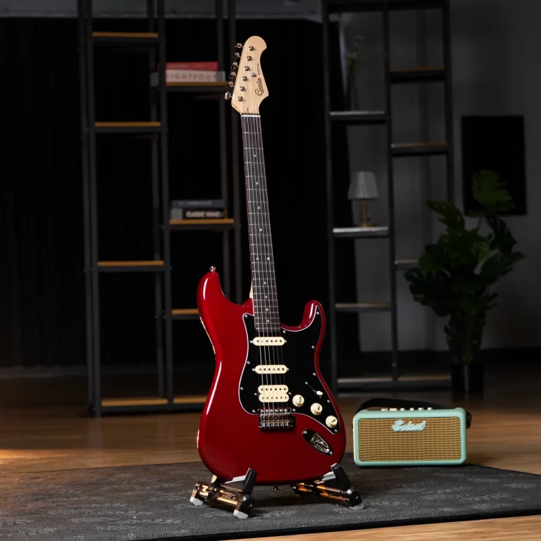 Red electric guitar on a stand in a music studio, with a small turquoise amplifier nearby on a wooden floor. ขายราคาพิเศษ