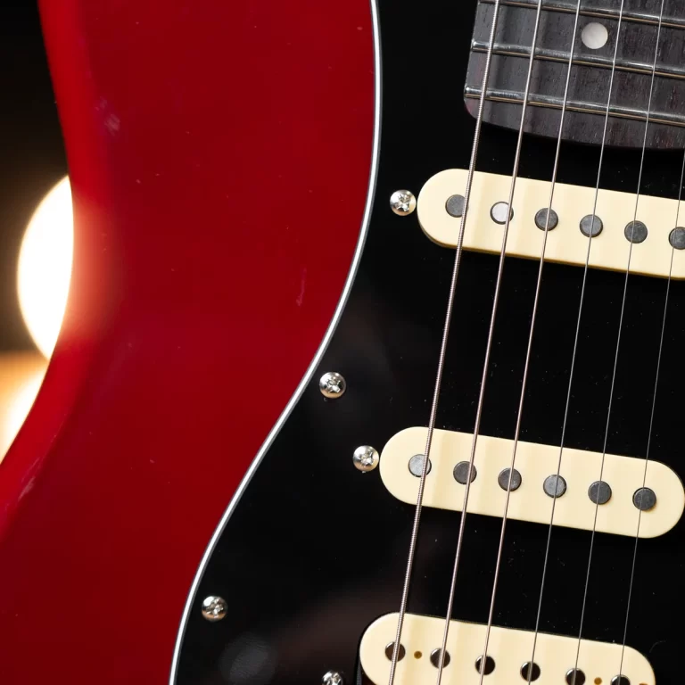 Close-up of a red and black electric guitar body with cream pickups and steel strings visible along the fretboard edge ขายราคาพิเศษ