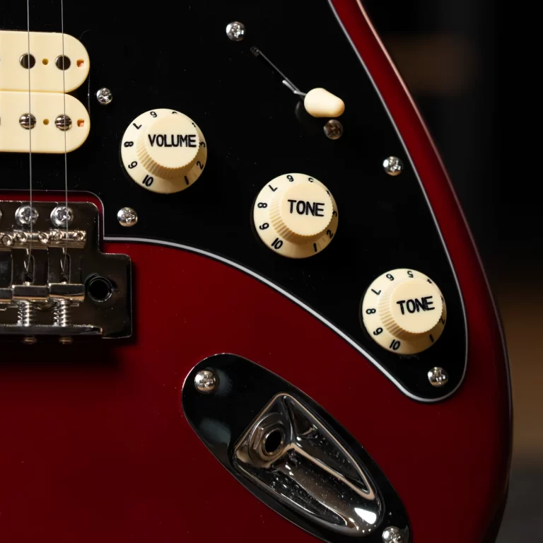 Close-up of a red electric guitar showing cream volume and tone knobs on a black pickguard. ขายราคาพิเศษ