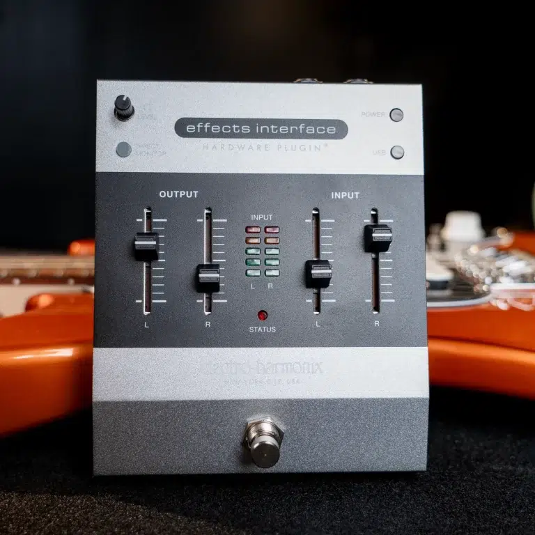 Front view of a silver and gray guitar effects interface with input/output sliders and status LEDs on a dark surface, plus a footswitch at the bottom. ขายราคาพิเศษ
