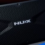 Close-up of a black speaker grille with the white NUx logo visible in the center. ขายราคาพิเศษ