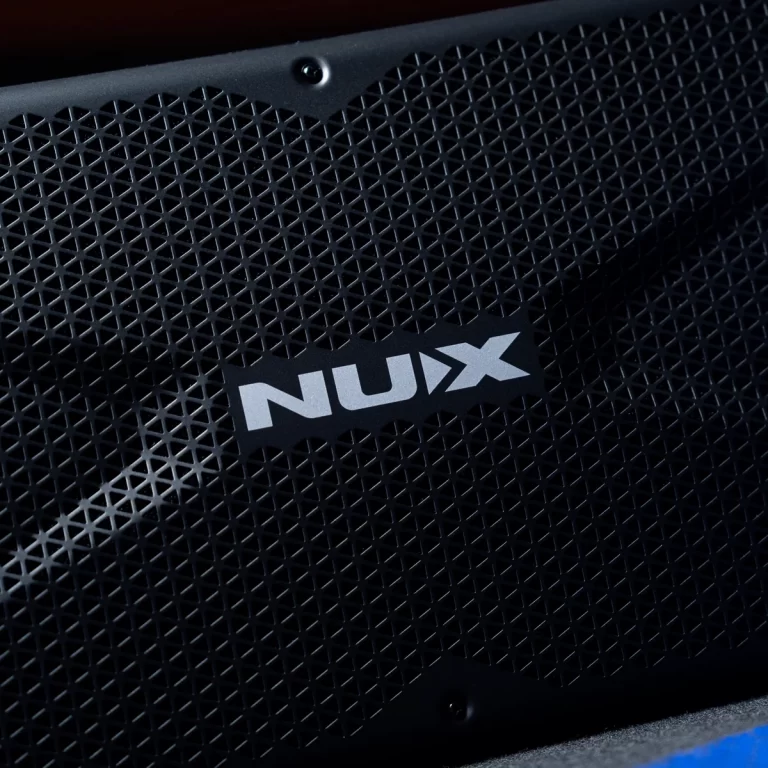 Close-up of a black speaker grille with the white NUx logo visible in the center. ขายราคาพิเศษ