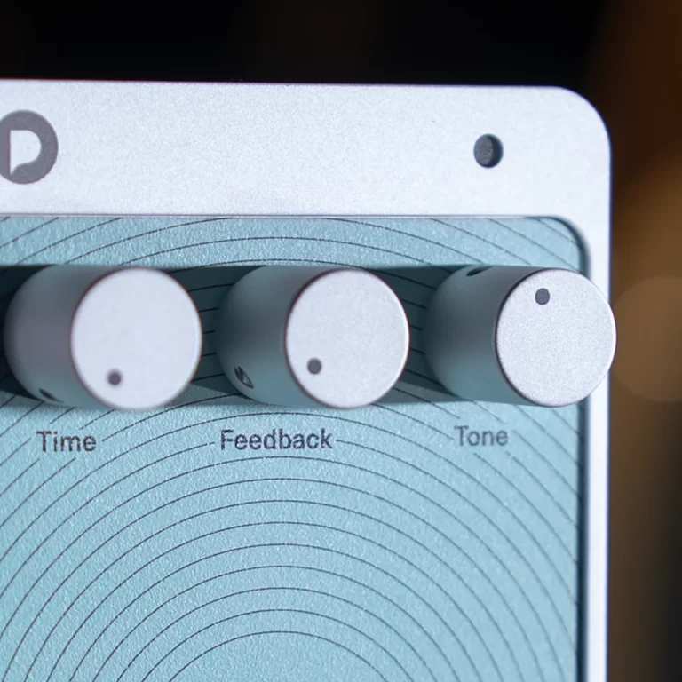 Close-up of a guitar effects pedal with three white knobs labeled Time, Feedback, Tone. ขายราคาพิเศษ