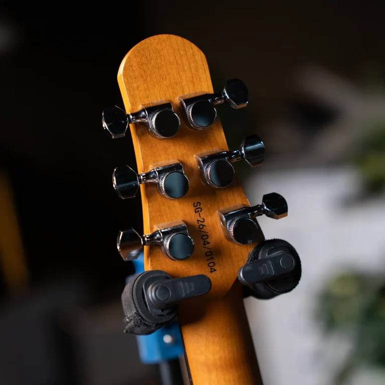 Close-up of a guitar headstock with six chrome tuning pegs on a warm wooden neck. ขายราคาพิเศษ