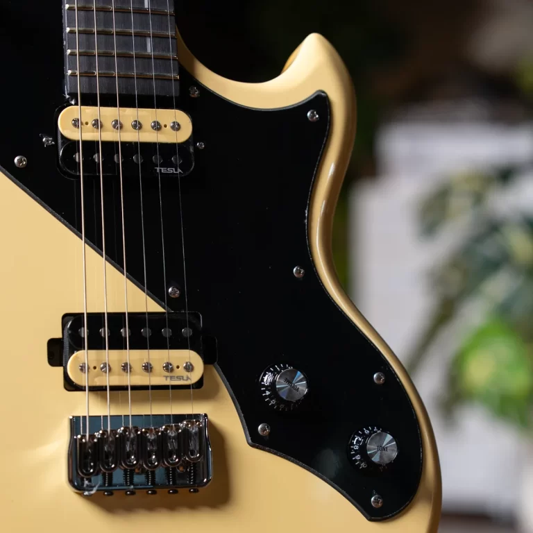 Close-up of a cream-colored electric guitar with a black pickguard, two cream pickups, and a chrome bridge. ขายราคาพิเศษ