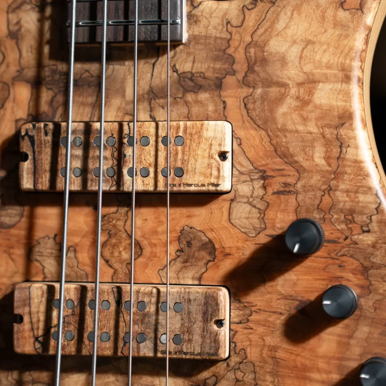 Close-up of a wooden electric bass guitar showing two pickups and four strings. ขายราคาพิเศษ
