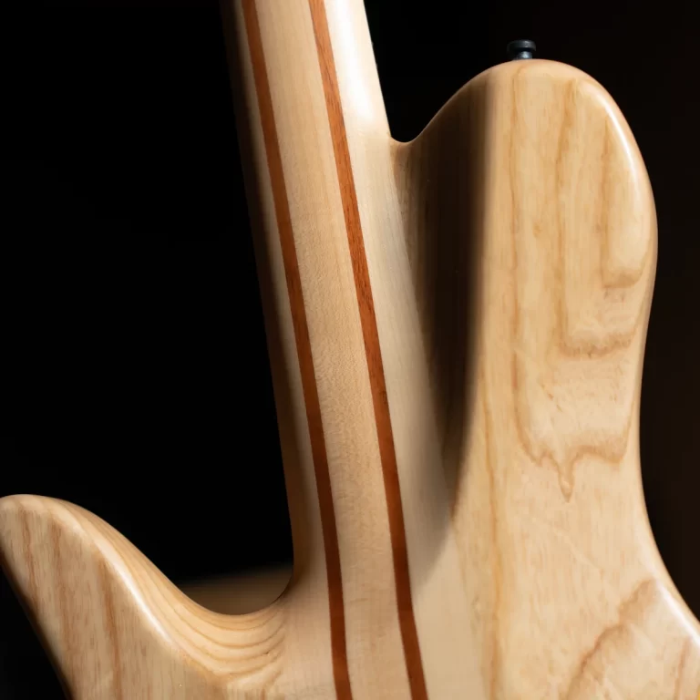 Close-up of a light wood guitar neck and body joint, showing laminated stripes and smooth finish. ขายราคาพิเศษ
