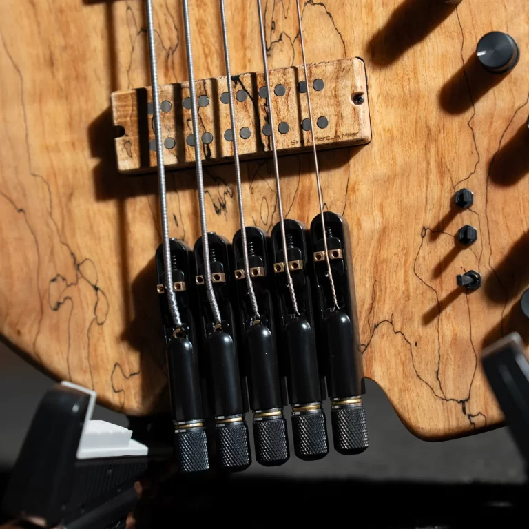 Close-up of a wooden electric guitar body showing the bridge saddles and six strings. ขายราคาพิเศษ