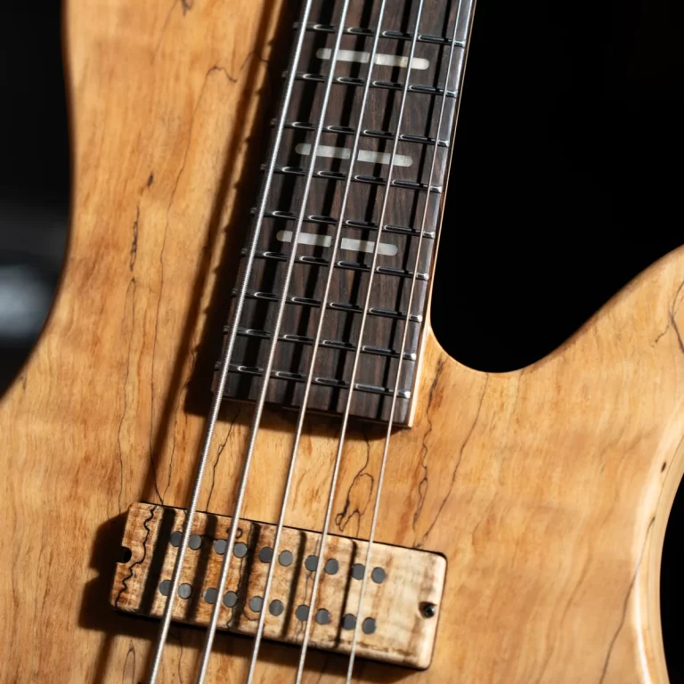 Close-up of a natural-wood electric guitar showing strings, frets, and a wooden pickup bridge on a carved body ขายราคาพิเศษ