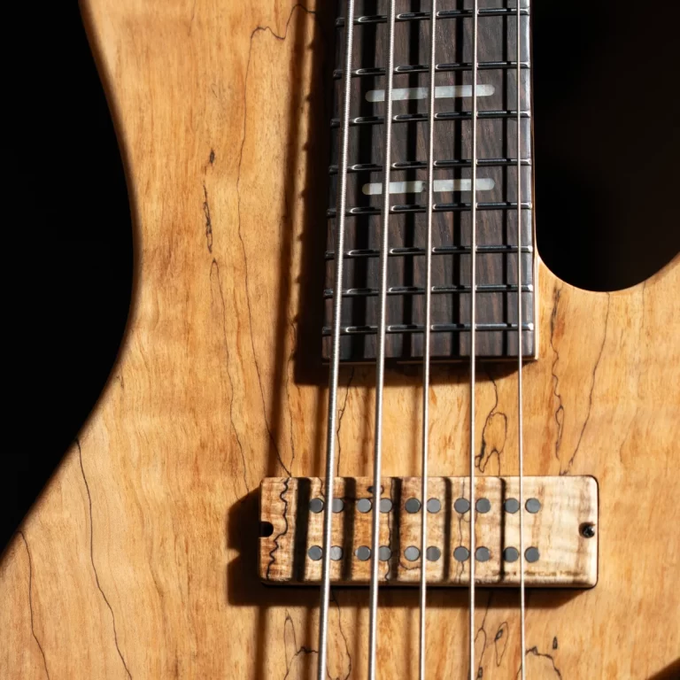 Close-up of a natural-finish electric guitar body, showing the bridge, six strings, and a dark fretboard with metal frets and pickups above the bridge. ขายราคาพิเศษ