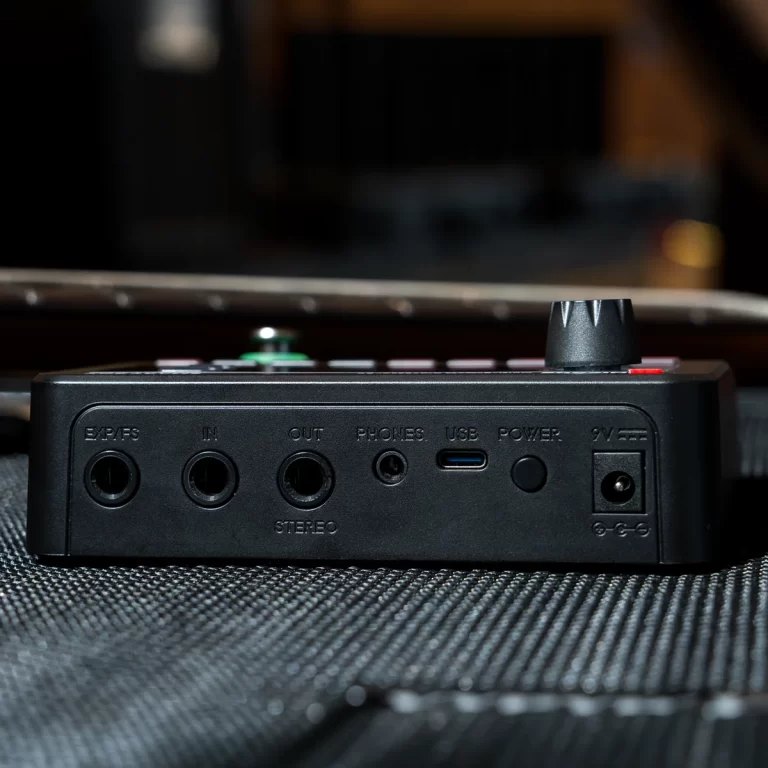 Close-up of a black audio interface showing rear ports: IN, OUT, PHONES, USB, POWER, 9V, on a textured surface with a knob on top ขายราคาพิเศษ