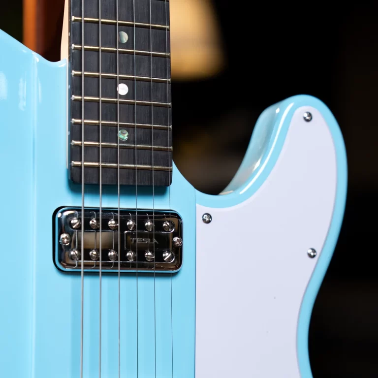 Close-up of a light-blue electric guitar showing the fretboard, strings, and chrome pickup against a dark background. ขายราคาพิเศษ